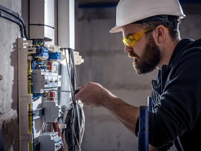 male-electrician-works-switchboard-with-electrical-connecting-cable_169016-16352